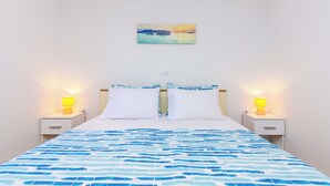 Een hotelkamer met een bed, twee nachtkastjes met lampen, een wandlamp en een aan de muur hangend schilderij.
