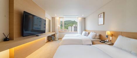Une chambre d’hôtel avec une télévision posée sur une étagère en bois, deux lits, une table de chevet avec une lampe et une fenêtre donnant sur des immeubles.