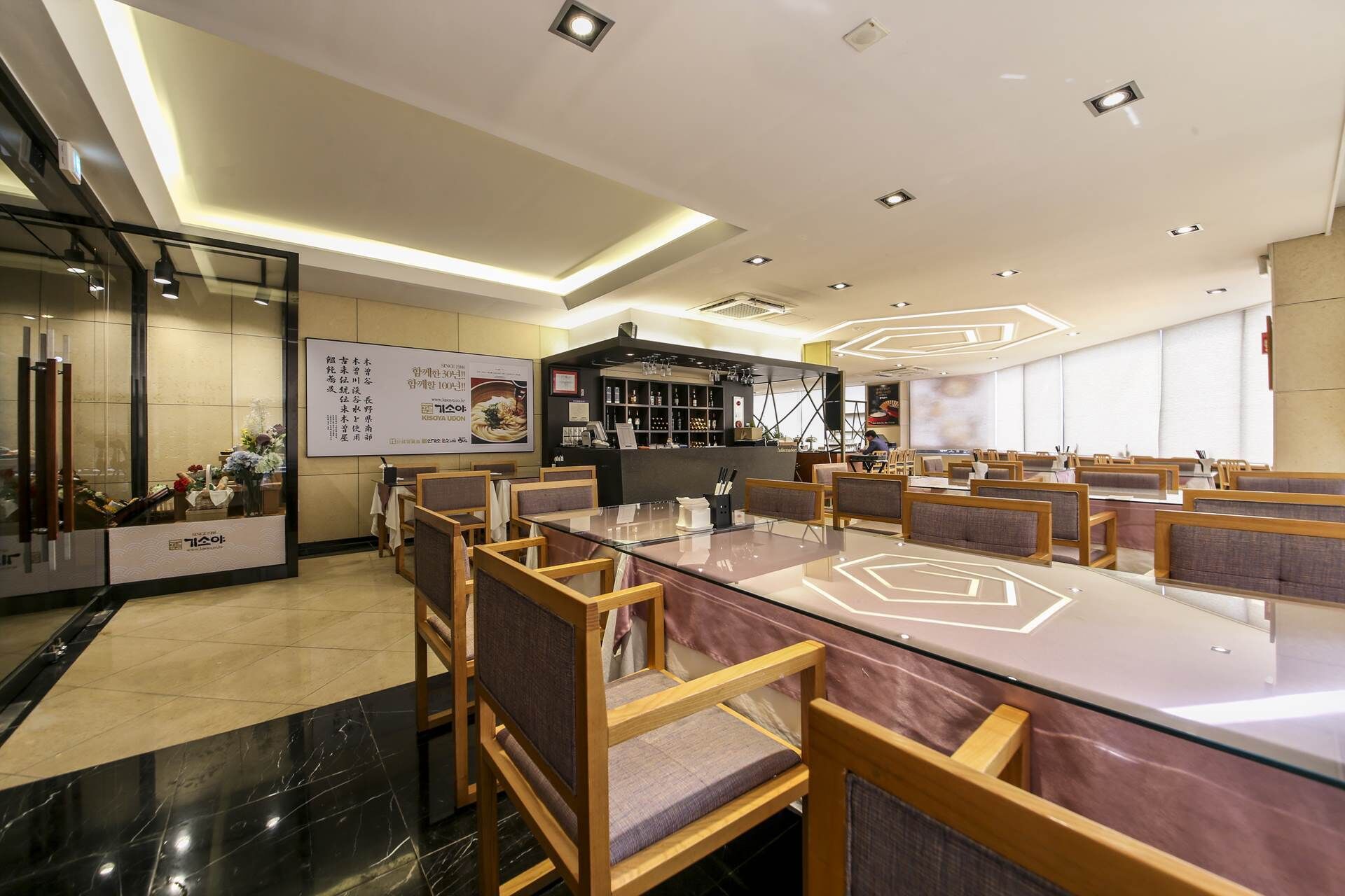 A modern dining area with a long table, multiple chairs, and a bar counter.