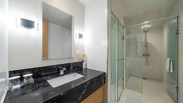 Un baño moderno con encimera de mármol negro, un espejo grande y cabina de ducha con paredes de vidrio.