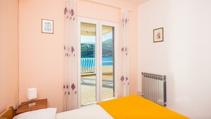 Une chambre d’hôtel avec un lit, une table de chevet, un radiateur et une vue sur un balcon donnant sur une piscine.