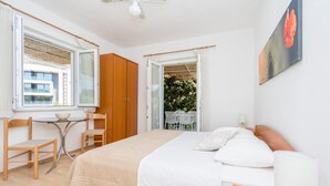 Un dormitorio con cama, mesita de noche, lámpara y ventana con vistas al verdor.