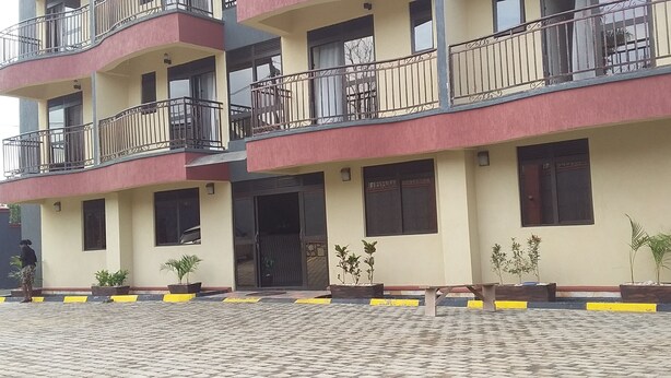 Un immeuble à plusieurs étages doté de balcons, de plantes en pot et d’un hall d’entrée carrelé.