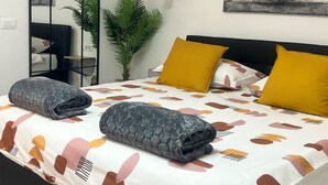 Un dormitorio moderno con una cama, un espejo, una planta y un cuadro en la pared.