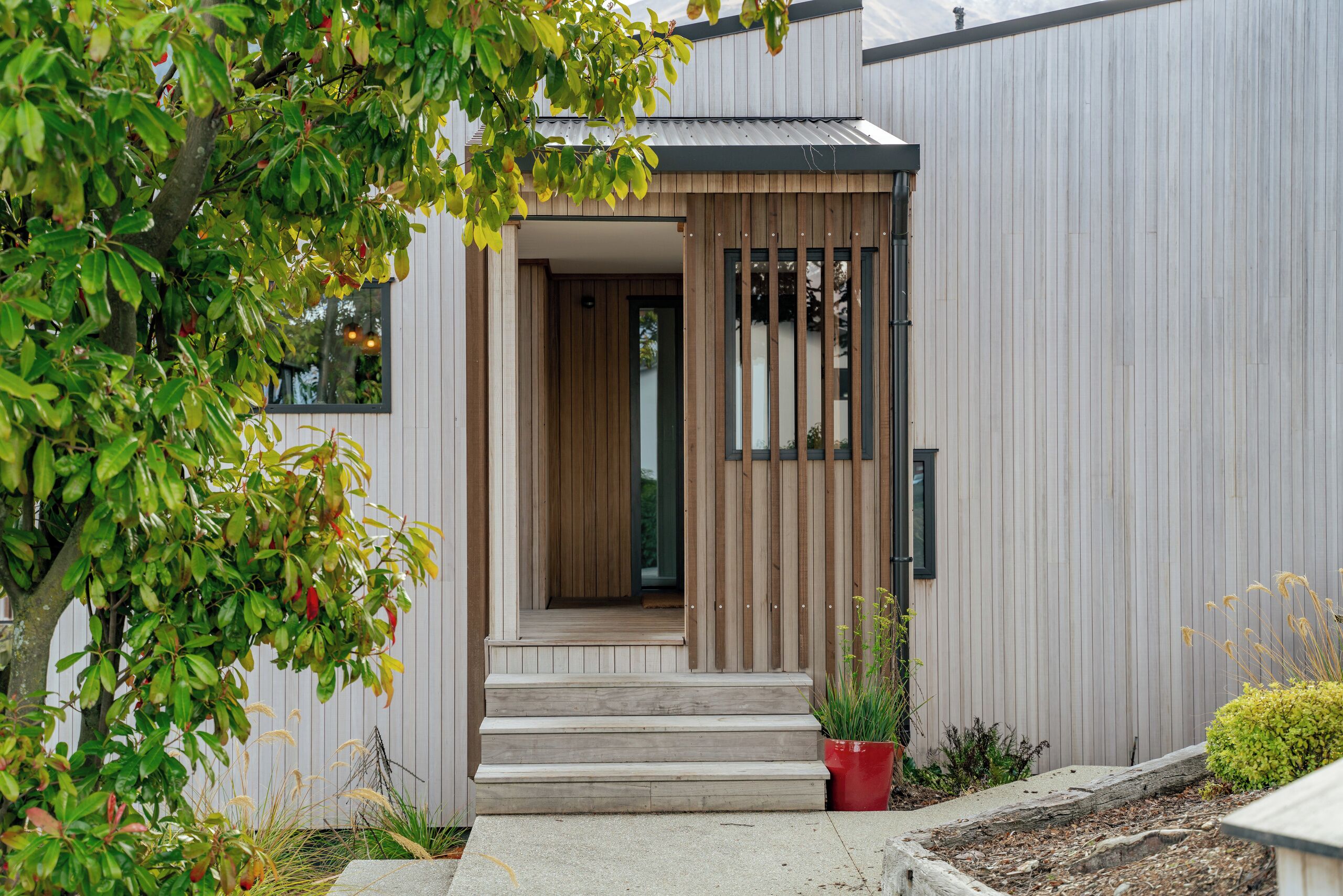 A modern building with a wooden door and steps leading to a porch.