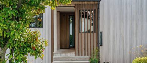 A modern building with a wooden door and steps leading to a porch.
