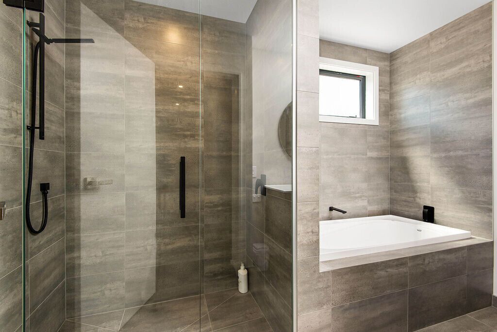 A modern bathroom with a glass-enclosed shower, a freestanding bathtub, and a built-in sink.