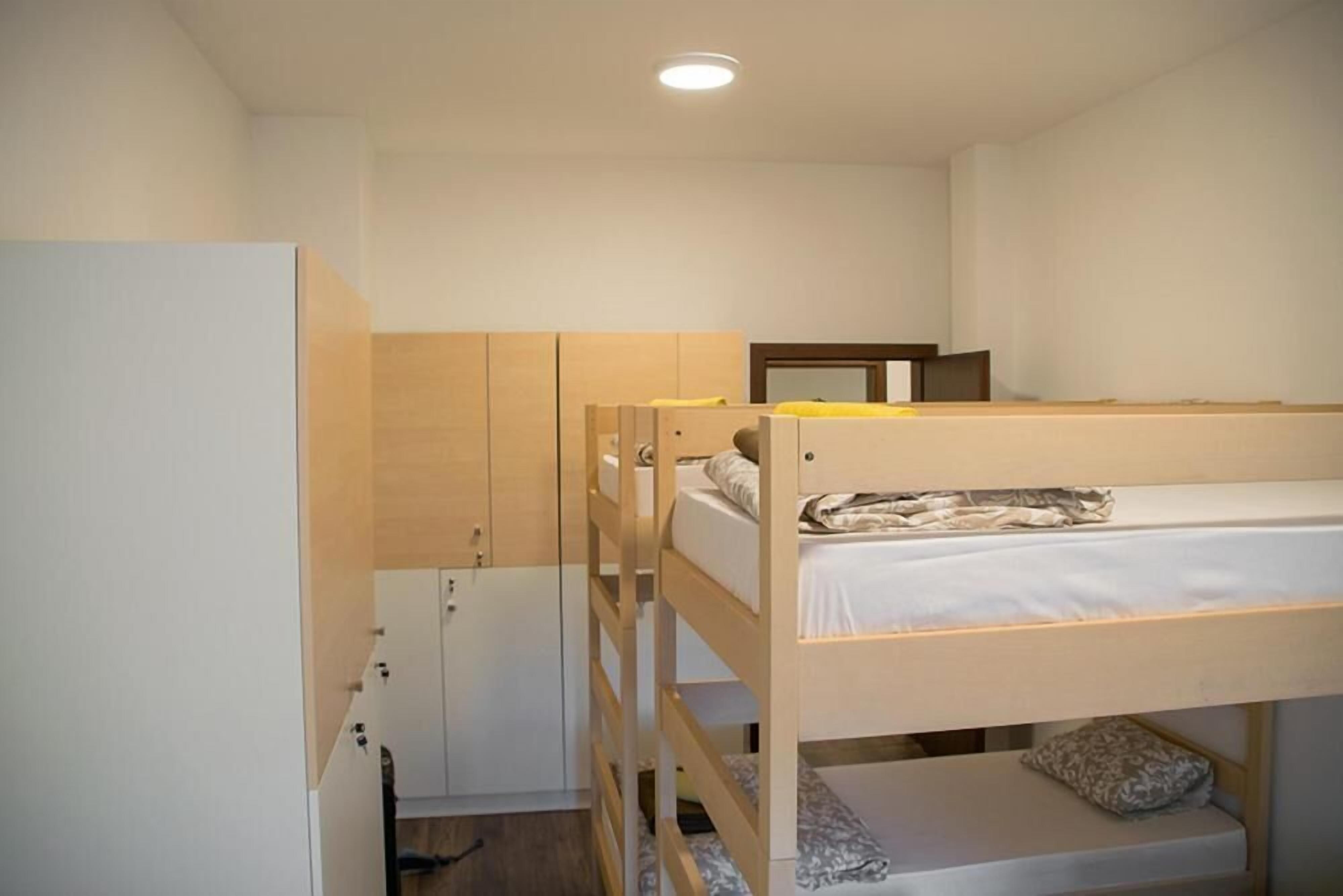 Een slaapkamer met een stapelbed, een garderobe en een spiegel.