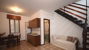 A compact living space with a kitchenette, a dining area, and a sofa. - Ville Annamaria (Lignano Sabbiadoro)
