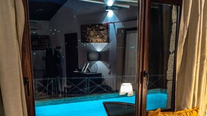 Una stanza con un divano giallo, una finestra vista piscina e una lampada su un tavolo.