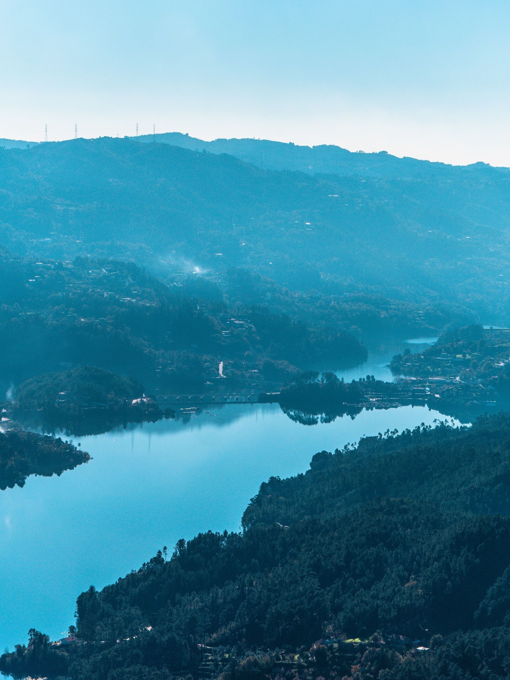 Ein Panoramablick auf eine gebirgige Landschaft mit einem großen Gewässer, das die umliegenden Hügel spiegelt.