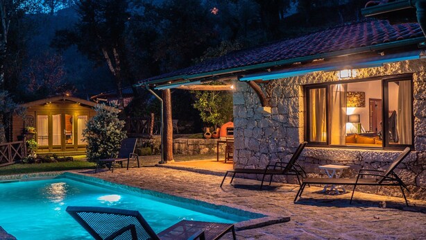 Un edificio de piedra con piscina y zona de estar al aire libre.