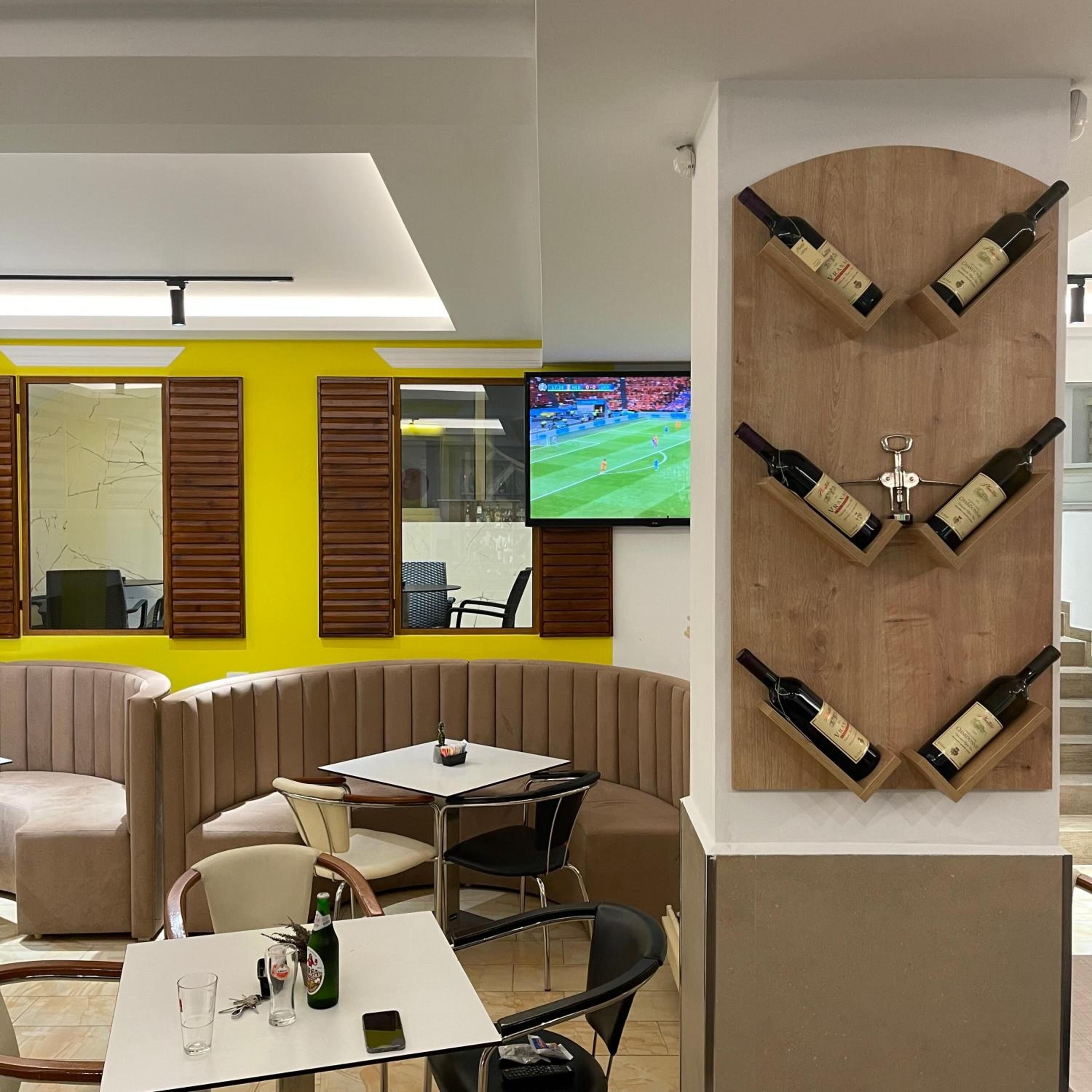 A modern lounge area with a TV, seating, and a wine display.