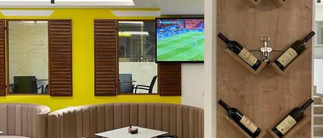 A modern lounge area with a TV, seating, and a wine display.