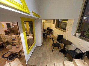 A modern interior with a dining area, a small kitchen, and a seating area with a view of the street. - Bobi Hotel (Shkodër)