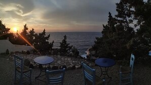 A patio with stone flooring, a round table, and two chairs. - Daidalos Hotel (Ikaria)