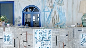 A room with a blue-framed door, a tiled wall with a geometric pattern, and a tiled floor. - Daidalos Hotel (Ikaria)