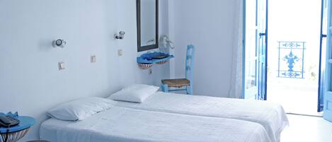 Habitación con dos camas, un espejo, un teléfono y un taburete pequeño.