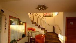 A staircase with a handrail, a chair, and a window with curtains. - Edelweiss Ladis (Ladis)