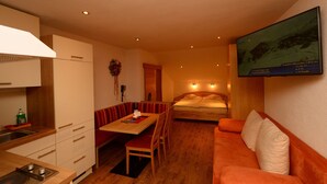 A compact hotel room with a kitchenette, a dining area, a sofa, and a bed. - Edelweiss Ladis (Ladis)