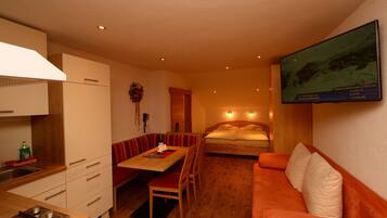 A compact hotel room with a kitchenette, a dining area, a sofa, and a bed.