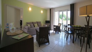 Ein Wohnzimmer mit einer Couch, Sesseln, einem Esstisch und einem Fernseher.