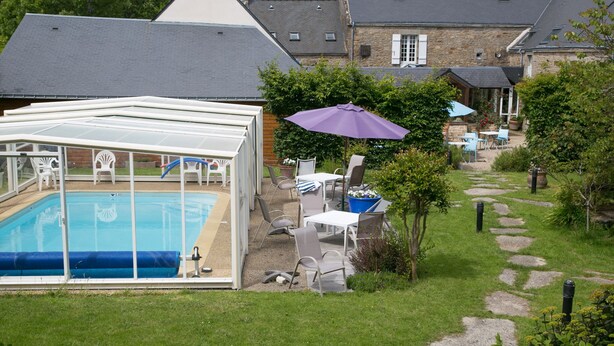 Ein Garten mit Swimmingpool, Sitzgelegenheiten im Freien und einem gepflasterten Weg.