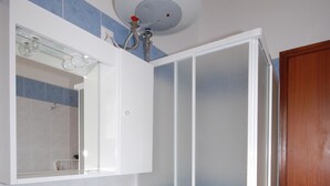 A bathroom with a white sink, a mirror, and a shower enclosure. - Ville Canarino (Lignano Sabbiadoro)