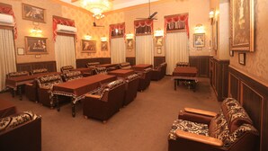 Une salle de réunion formelle, dotée de longues tables, de canapés à motifs et de lustres.