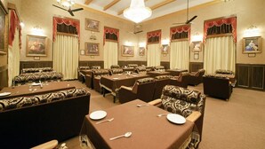 Une salle à manger élégante, dotée de plusieurs tables et chaises, de lustres et d’œuvres d’art encadrées accrochées aux murs.