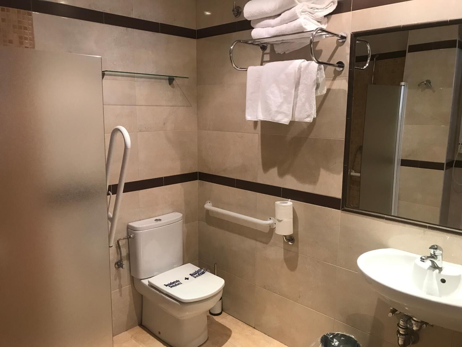 Une salle de bain moderne équipée d’un WC, d’un lavabo, d’une douche et d’un porte-serviettes.