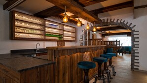 A bar area with wooden bar stools, shelves with glassware, and exposed wooden beams. - Bergnest - Frühstückspension Katschberg (Sankt Michael im Lungau)