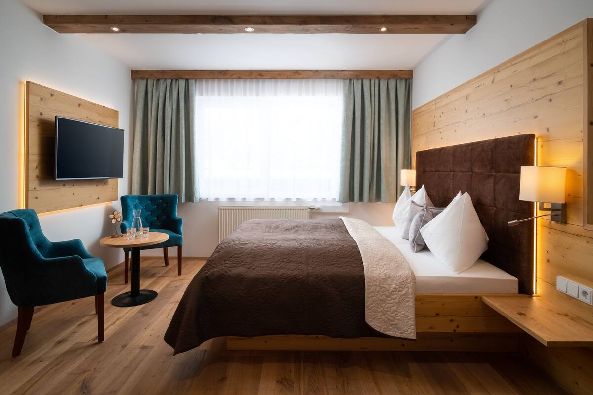 Ein Hotelzimmer mit Bett, Fernseher, Schreibtisch und Stuhl.