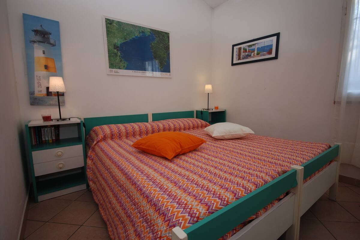 Ein ordentlich eingerichtetes Schlafzimmer mit Bett, zwei Nachttischen, einem Beistelltisch und Wandbildern.