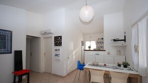 A dining area with a table, chairs, and a hanging light fixture. - Ville La Tana - Paola (Lignano Sabbiadoro)