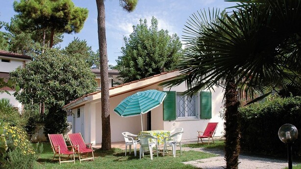 A patio with outdoor seating, a table, and a striped umbrella. - Ville La Tana - Paola (Lignano Sabbiadoro)
