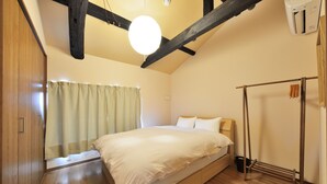 A bedroom with a wooden bed, a hanging light fixture, and a wooden wardrobe. - Shiki Tofukuji (Kyoto)