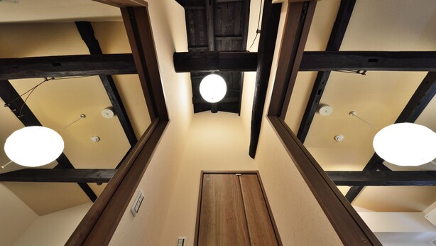 A narrow hallway with wooden beams and a central door, leading to a room with a ceiling light. - Shiki Tofukuji (Kyoto)