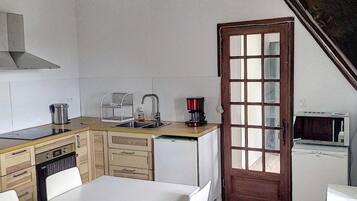 Una cocina compacta con vigas de madera, una mesa blanca y sillas.