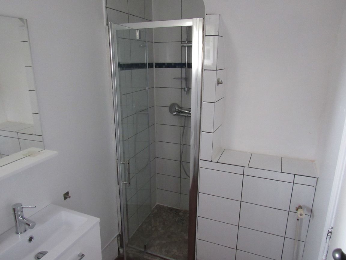 A bathroom with a glass-enclosed shower, a white sink, and a mirror.