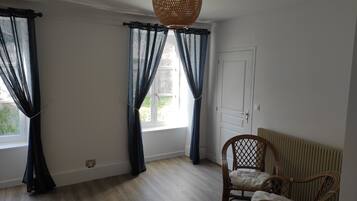 A room with a large window, a wicker chair, and a radiator.