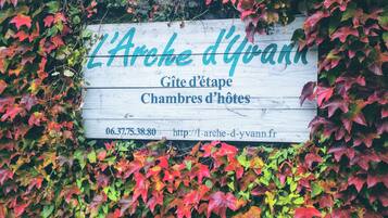 A wooden sign with text indicating 'L'Arche d'Yvann' and 'Gîte d'étape Chambres d'hôtes'.