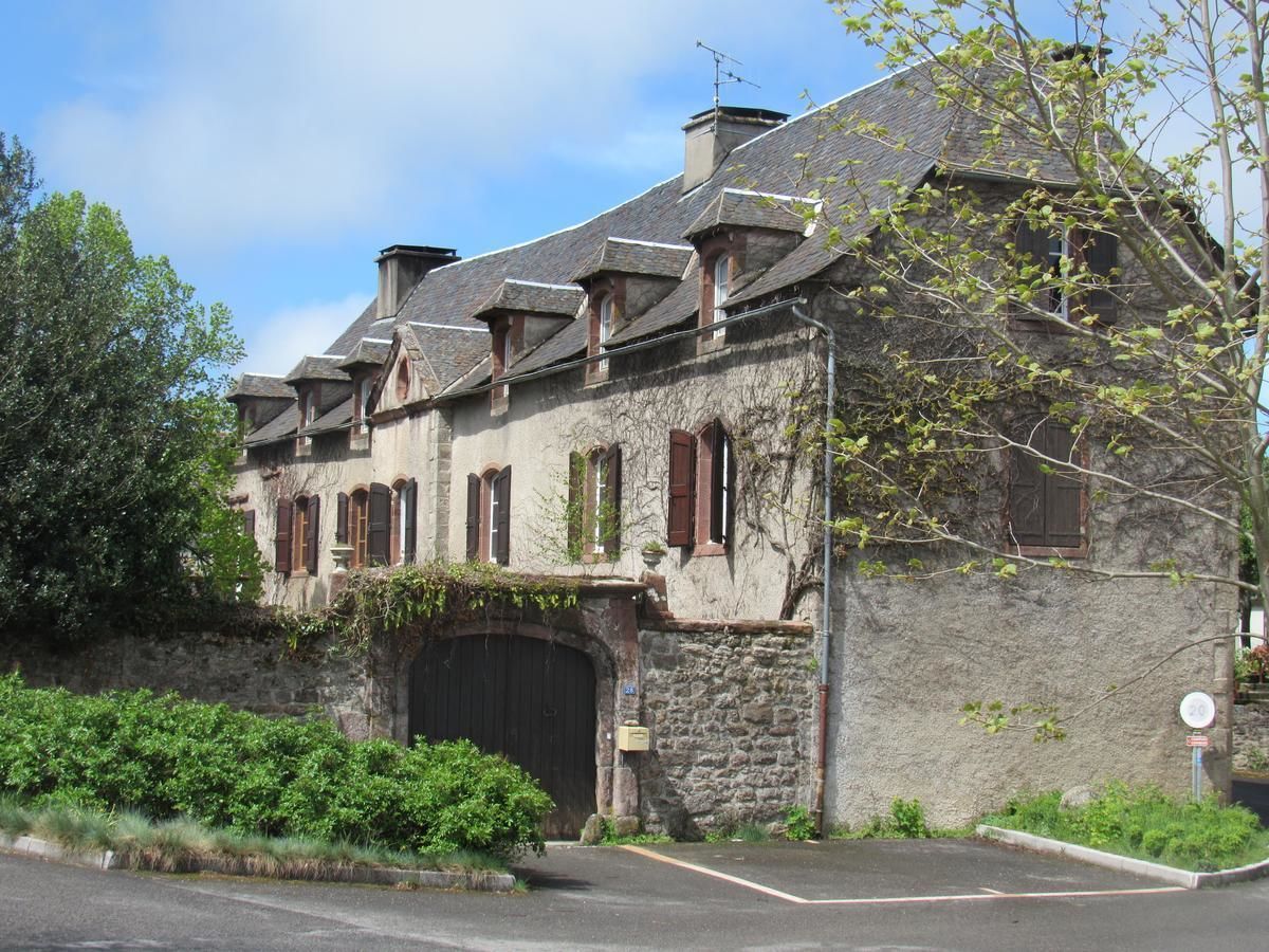A historic stone building with a large central entrance and multiple windows with shutters.