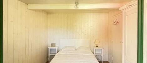 Une chambre avec un lit simple, deux tables de chevet, une chaise et une armoire.