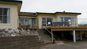 A two-story house with a wooden deck and a stone retaining wall.