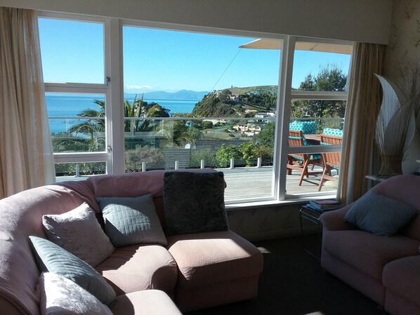 A living room with a large window overlooking a scenic view of a beach and hills.