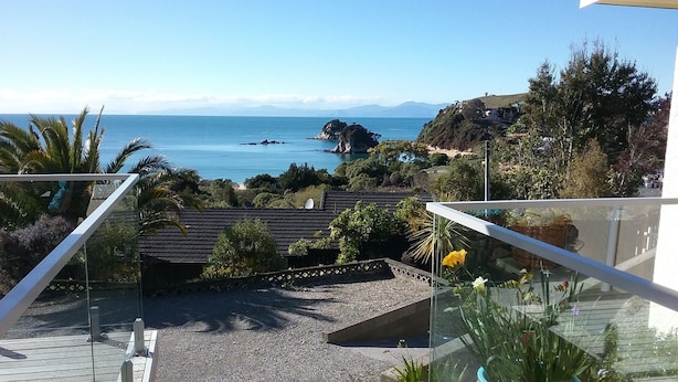 A balcony with a view of the sea, a gravel path, and potted plants.
