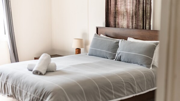 A neatly made bed with a striped bedspread, a wooden headboard, and two pillows.