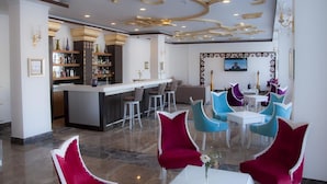 A modern hotel lobby with a bar area, seating with vibrant chairs, and a decorative ceiling. - Life Elite Hotel (Manavgat)