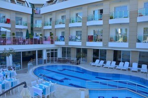 A multi-level hotel with a central swimming pool, outdoor seating, and balconies with railings. - Life Elite Hotel (Manavgat)